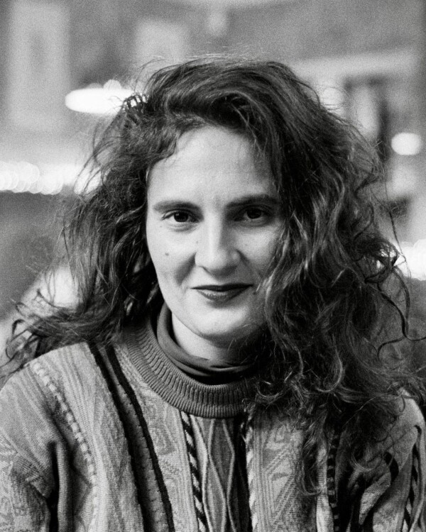 Tosia Bargiełowska Johnsen, Second Hand Dance Support Worker and Administration Coordinator with long curly hair, wearing a patterned high‑collar sweater, looking directly at the camera with a neutral expression against a softly blurred indoor background.